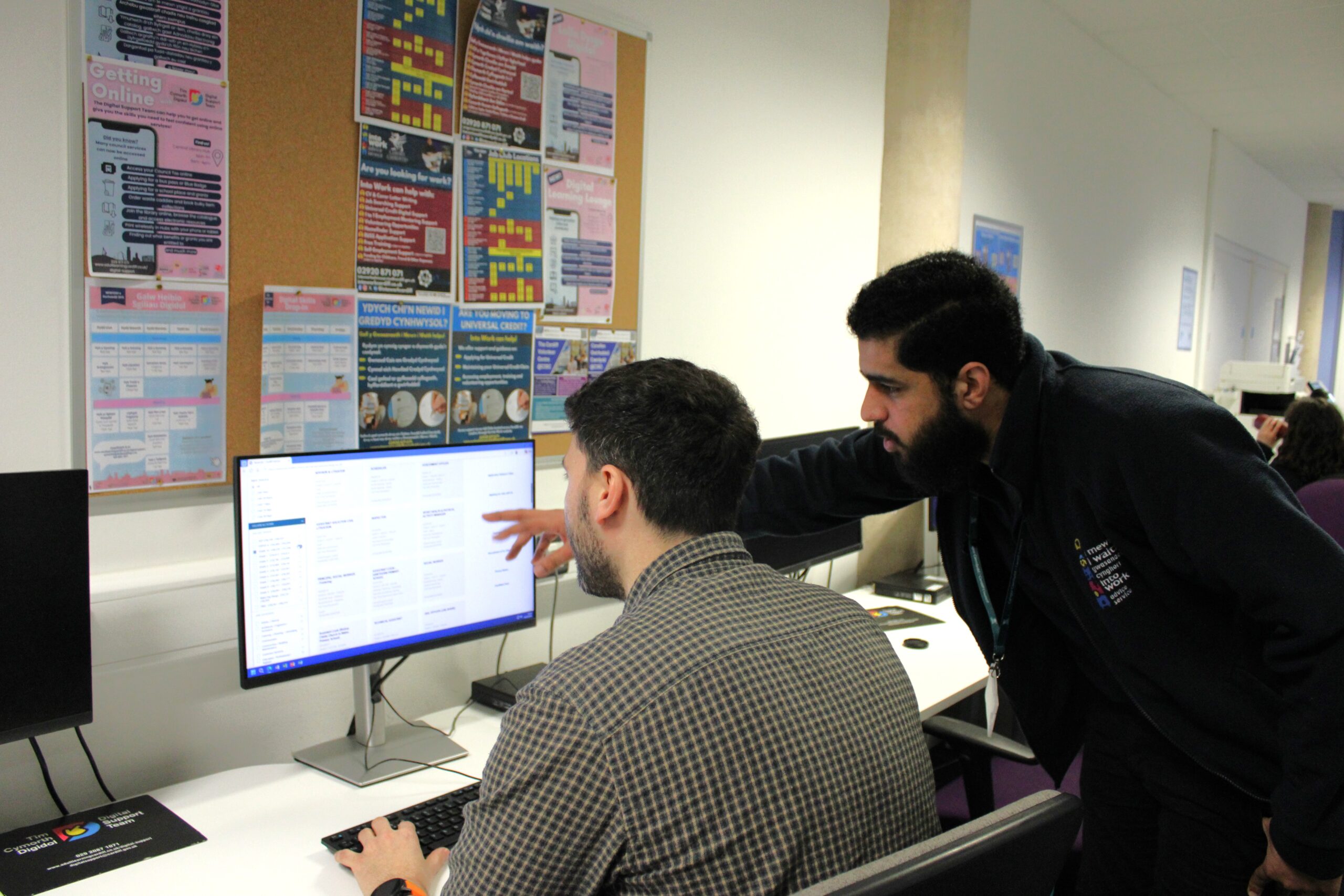 An image of an Into Work employee supporting a customer on a computer in Job Club.